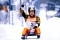 Georg Hackl sur sa luge en posture de vainqueur.