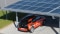 La foto mostra un posto auto coperto con moduli fotovoltaici sul tetto e un'auto elettrica in carica.